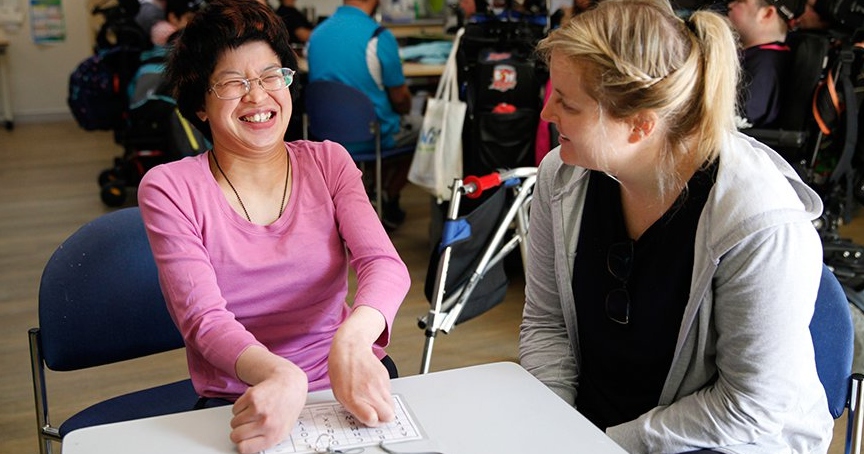 Two women sitting at a table laughing and talking